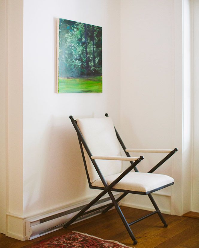 folding chair in a corner under a painting